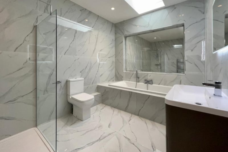The master bathroom features marble tiling, a fitted bath and walk in shower. 