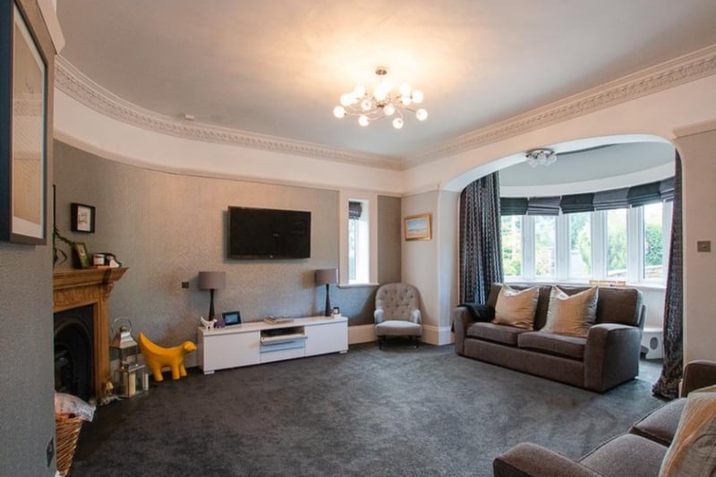 The spacious living room has lush carpets and a large bay window. 