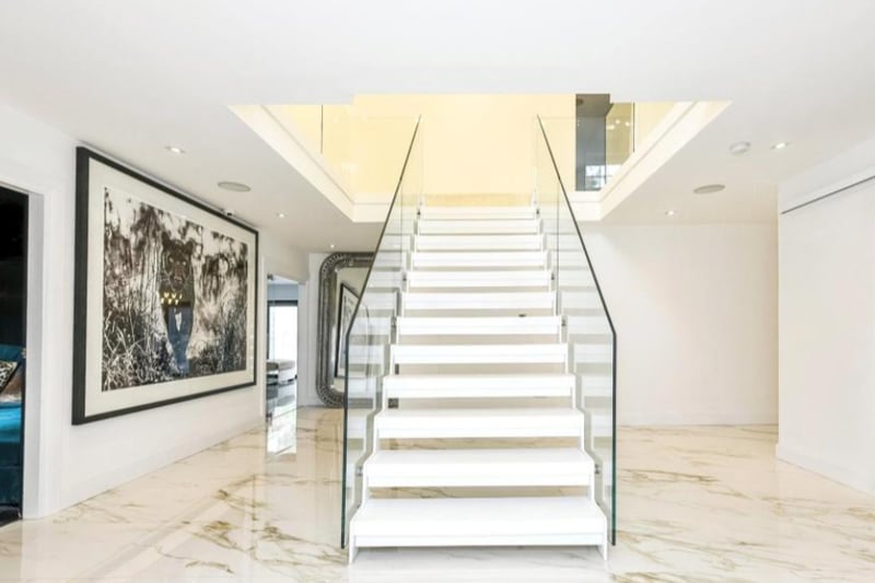 The property is luxurious and modern, with marble flooring and a unique glass staircase. 