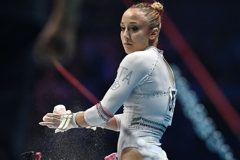 Italy’s Martina Maggio puts chalk on her hands as she competes during the Women’s Uneven Bars team final event. (Photo by BEN STANSALL/AFP via Getty Images)