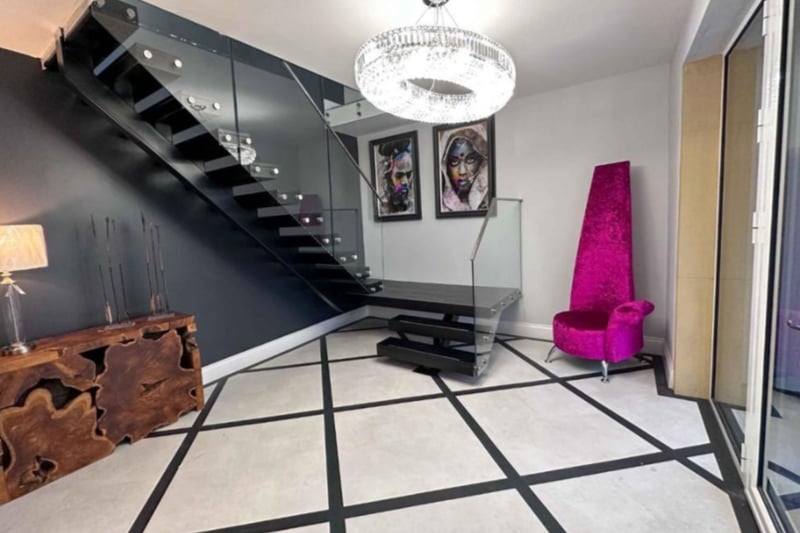 The property is a mix of modern and quirky, with the large hallway featuring unusual flooring and a floating staircase. 