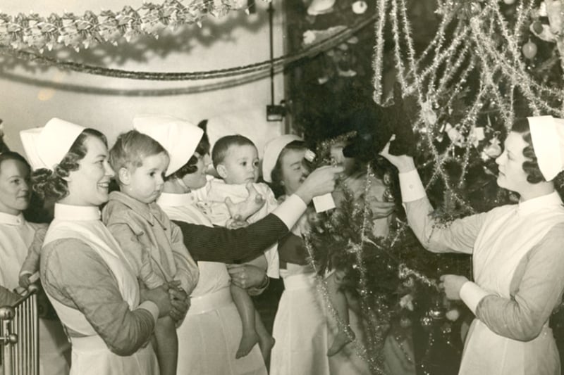 Nurses and a patients at the Liverpool Stanley Hospital at Christmas, 1937. A nurse next to the enormous Christmas tree is holding up a toy dog, probably to get the childrens’ attention for the photo - a tactic that has often been deployed for festive family photographs over the years! 