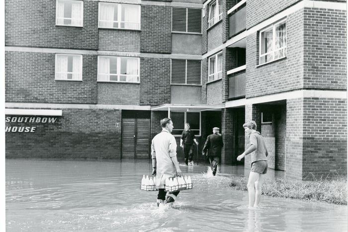 A milkman, wearing wellies, completes his rounds after the flooding. Southbow House was built in 1962, made up of 11 floors with 63 apartments housing elderly residents.