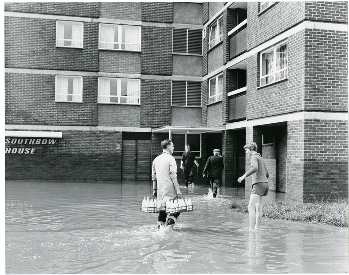 A milkman, wearing wellies, completes his rounds after the flooding. Southbow House was built in 1962, made up of 11 floors with 63 apartments housing elderly residents.
