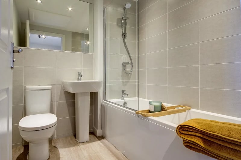 The modern first floor bathroom features recessed lighting, a sizeable bath, and a huge mirror 