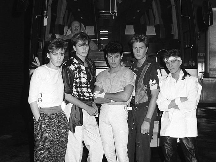 Keyboard player Nick Rhodes, bassist John Taylor, drummer Roger Taylor, singer Simon Le Bon and guitarist Andy Taylor of Duran Duran pose in front of their tour bus backstage at Wembley Arena in London, England on December 19, 1983. (Photo by Rogers/Express/Getty Images)