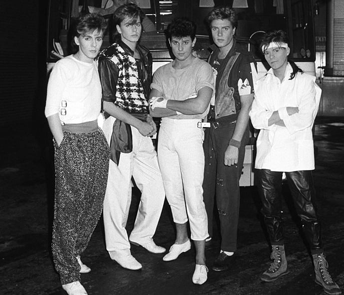 Keyboard player Nick Rhodes, bassist John Taylor, drummer Roger Taylor, singer Simon Le Bon and guitarist Andy Taylor of Duran Duran pose in front of their tour bus backstage at Wembley Arena in London, England on December 19, 1983. (Photo by Rogers/Express/Getty Images)