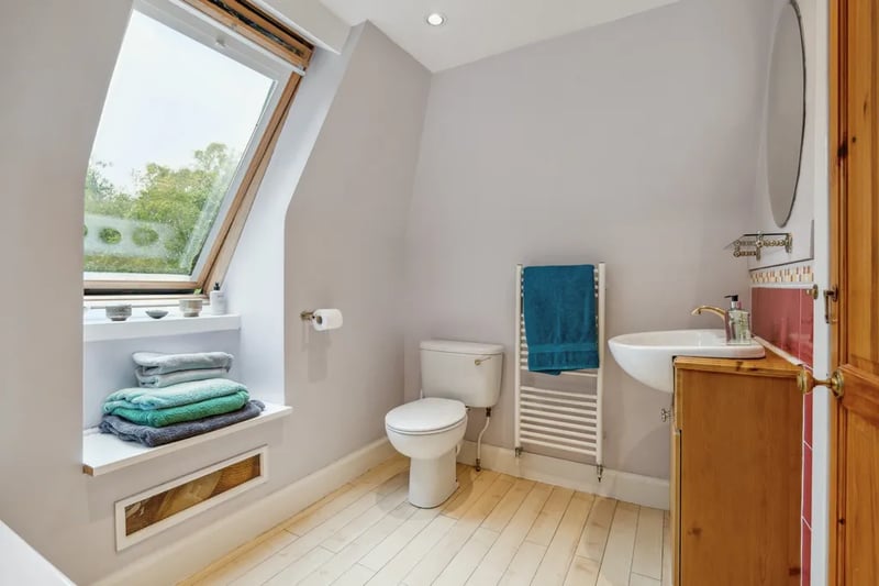 The principle en-suite offers a towel rack, a large circular mirror above a large wash basin