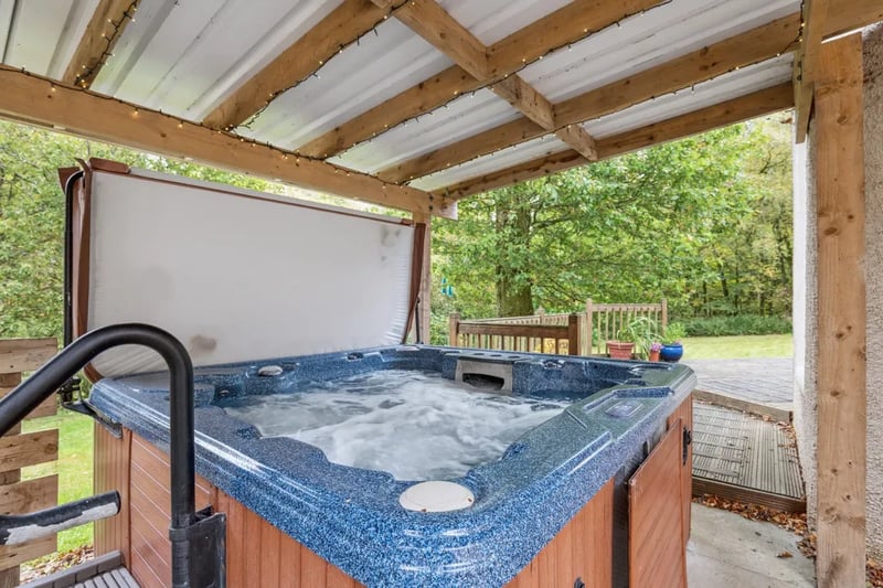 The property features a sheltered hot tub enclosure