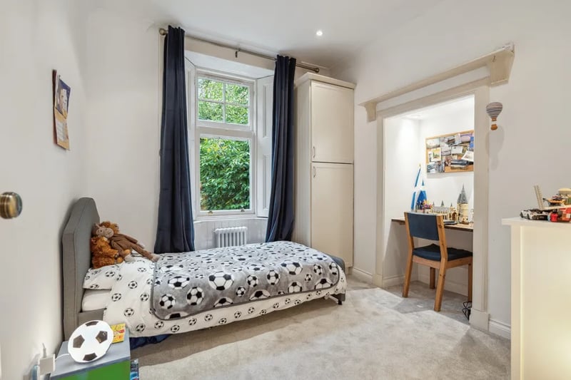 The first bedroom is ideal for a family, featuring designated desk space, and a window looking out to on the greenery