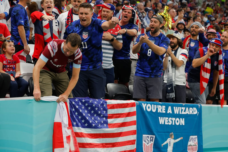 USA’s supporters (R) ask an England supporter (L) not to cover their flag.