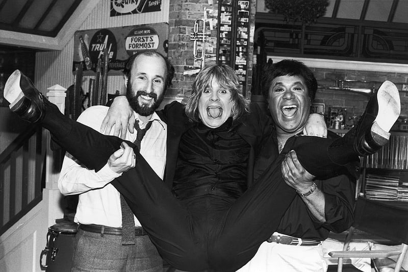 Ozzy Osbourne spreads his legs as he is held by MTV executive producer Julian Goldberg (L) and MTV VJ J.J. Jackson, circa 1982. Osbourne announced that he would establish a scholarship fund in the name of guitarist Randy Rhoads. (Photo by Hulton Archive/Getty Images) 