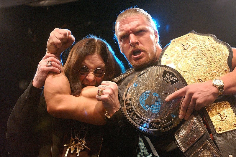 Ozzy Osbourne (L) pretends to bite the arm of pro-wrestler Tripple H at a news conference to announce the lineup for “Ozzfest” 2002 March 21, 2002 at the World Wrestling Federation headquarters in New York. (Photo by Spencer Platt/Getty Images)