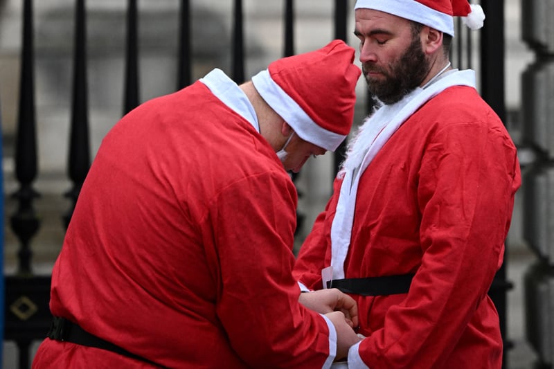 A runner receives assistance with his Father Christmas attire. (Photo by OLI SCARFF/AFP via Getty Images)