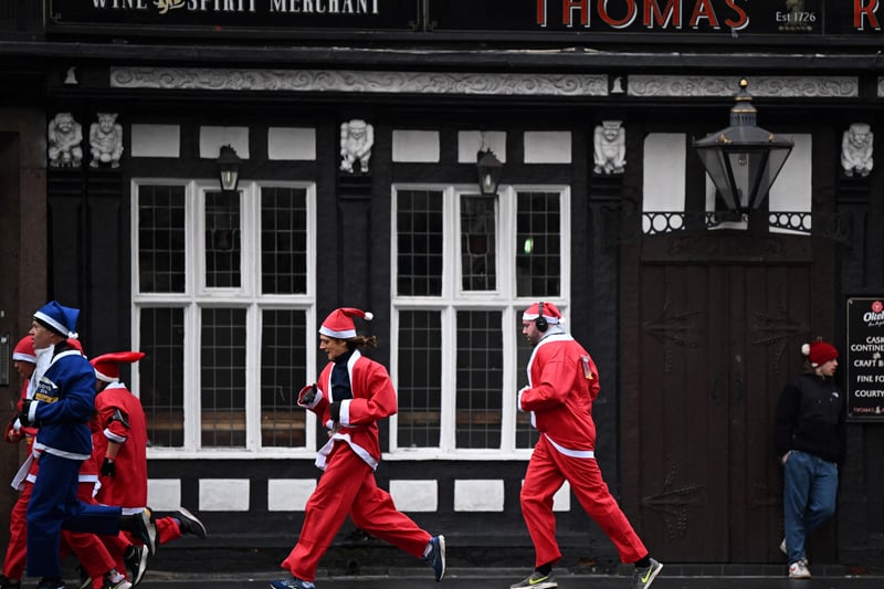 The runners head past the pub, without stopping for some festive spirits.  (Photo by OLI SCARFF/AFP via Getty Images)