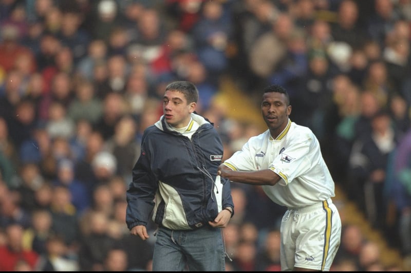 Lucas Radebe escorts a pitch invader off the turf during a Premiership clash with Derby in November 1997.