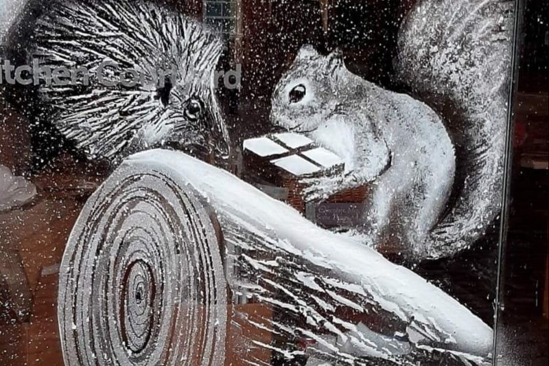 A charming woodland scene featuring a hedgehog and a squirrel as snow falls