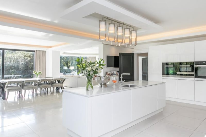 The large, open-plan kitchen area boasts beautiful fitted cabinets, a dining area and kitchen island.