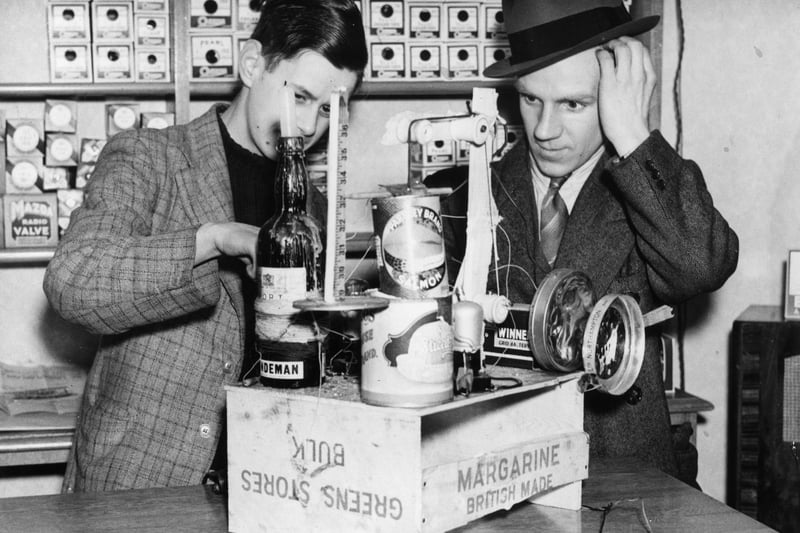 An assistant at Mr Meredith’s shop in Liverpool demonstrates a radio set built from old tins, a bottle, a clothes peg, a cigarette and some razor blades in 1937. (Getty Images)