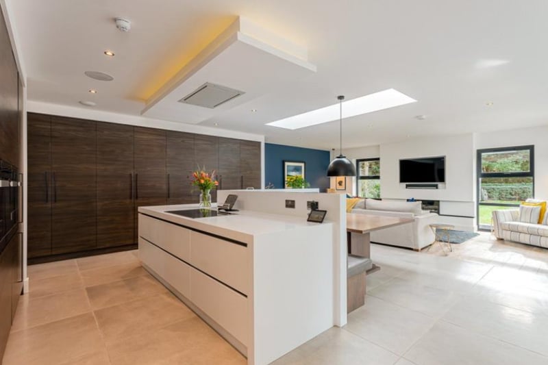 The kitchen area is modern and luxurious, with high quality fitted appliances and dark wooden cabinets.
