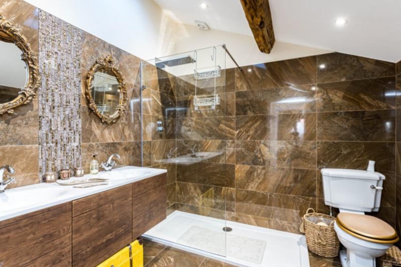 One of the en-suite bathrooms is themed in gold and bronze, with ‘his & hers’ sinks and a beamed ceiling.