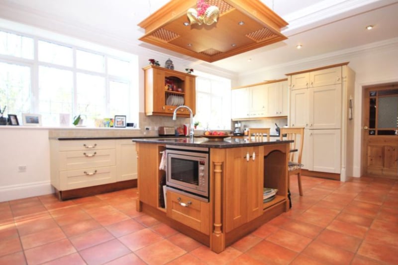 The large kitchen features an island workspace, fitted appliances and tiled flooring.
