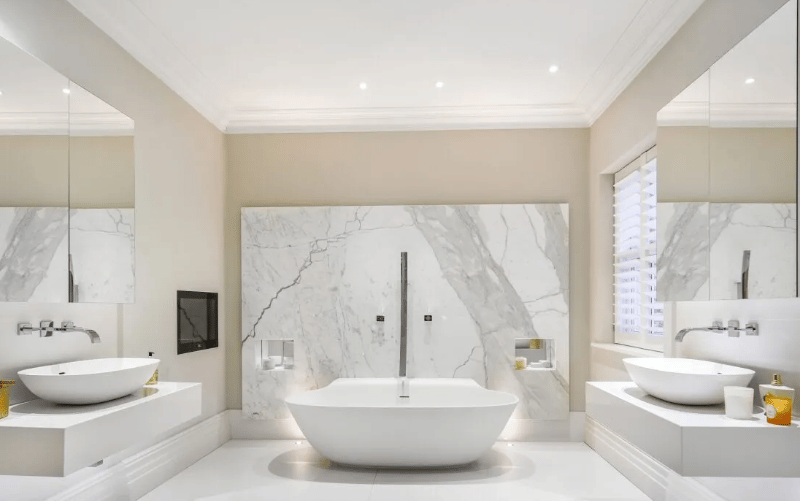 A sprawling bathroom complete with a wide bath and two huge sinks 