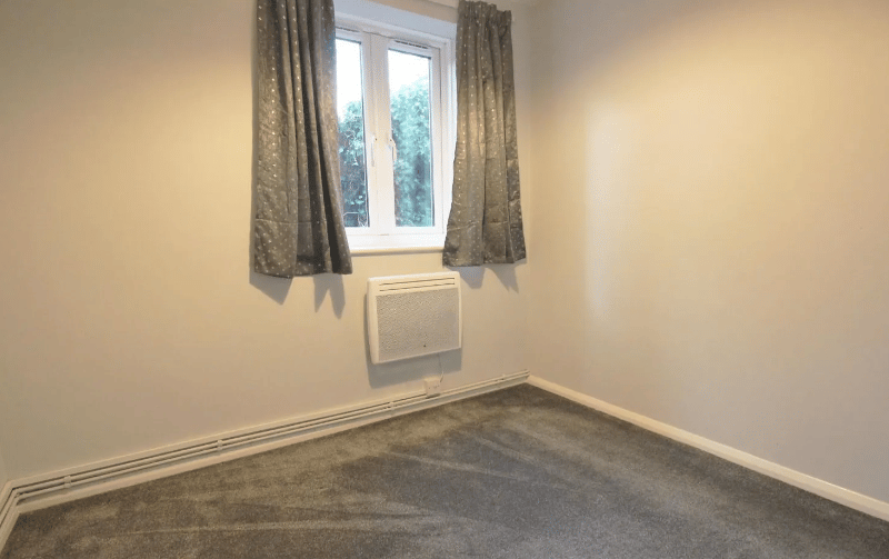 An image of the bedroom, with a small radiator and modern carpets