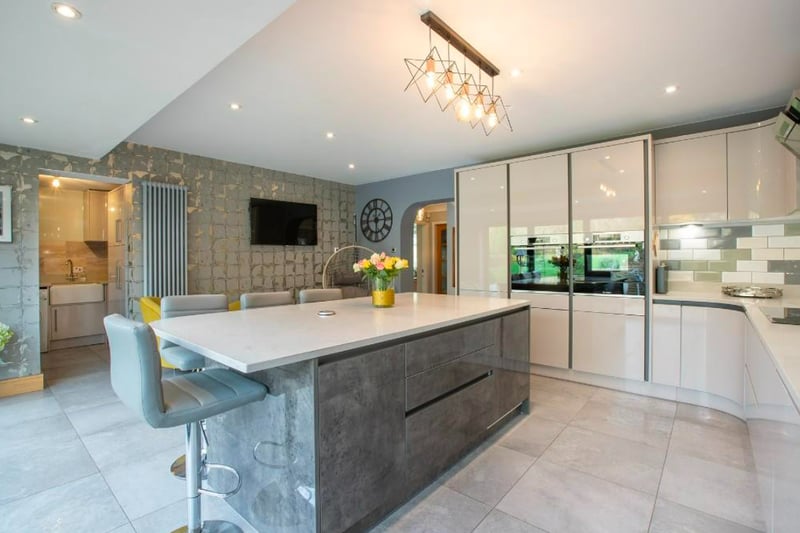 The refitted kitchen has a range of wall and base units, granite work surfaces with fitted sink and drainer, two electric ovens, five ring ceramic hob with extractor over, central island with breakfast bar, two bi-folding double glazed doors to rear patio/terrace and central heating radiator.  (Photo - Rightmove)