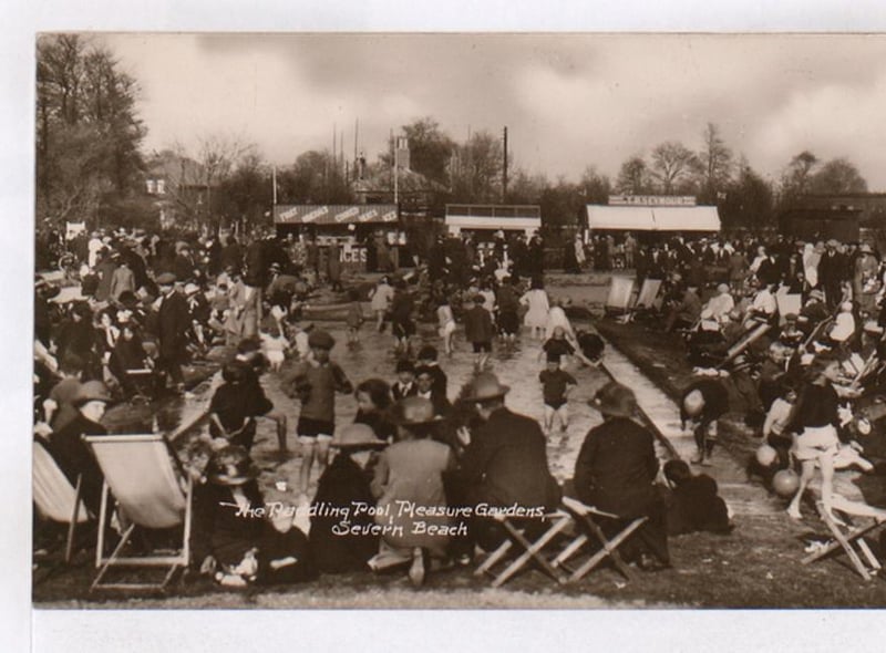Crowds gather as children play in a paddling pool.