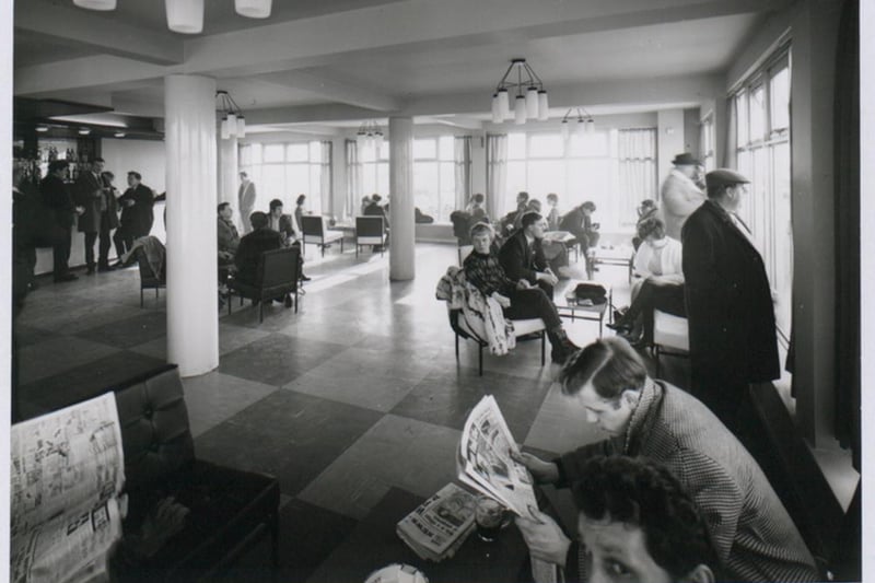 Passengers wait for their flights, some reading newspapers, inside Bristol Airport’s lounge.