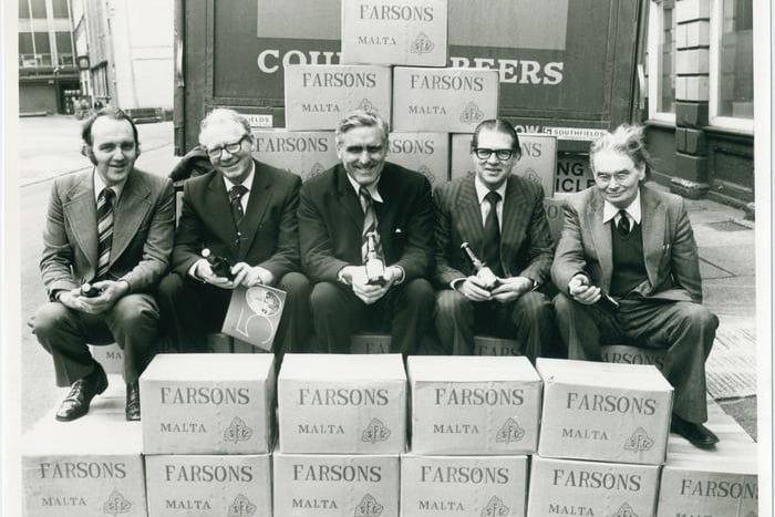 A group of men pose against Courage’s Beer Van holding Farsons Malta.