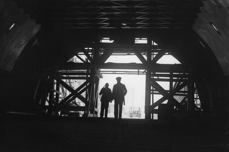 Two workmen stand framed in the entrance to the nearly-completed Mersey Tunnel, which connects Birkenhead and Liverpool.