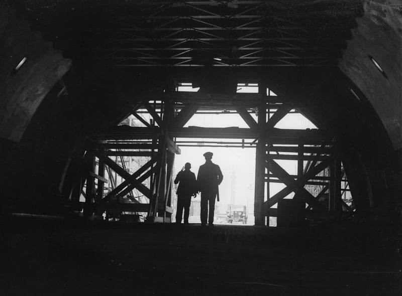 Two workmen stand framed in the entrance to the nearly-completed Mersey Tunnel, which connects Birkenhead and Liverpool.