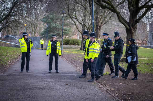 Police officers walk the cordon in the park