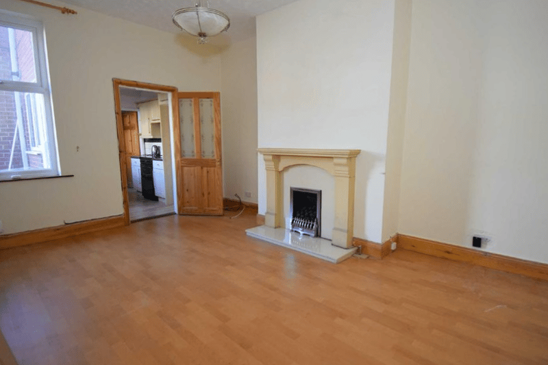 The main room of the two-bedroom property, showcasing a large area with laminate flooring and an elegant fireplace