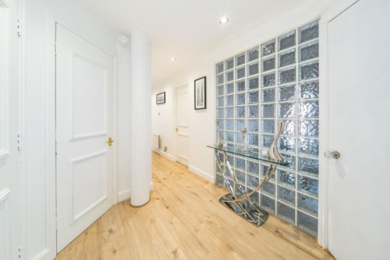 The luxury apartment has a large, bright hallway with wooden flooring.