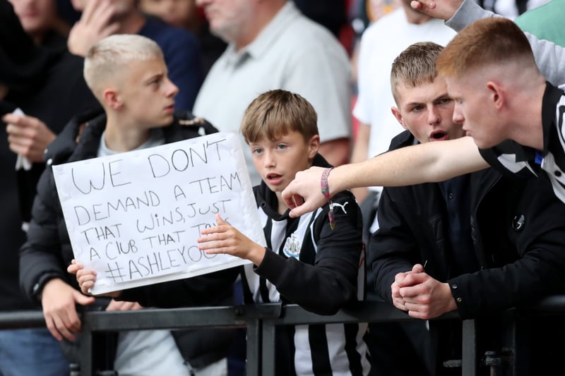 A fan of Newcastle United holds aloft a sign in protest of the current ownership prior to the Premier League match between Watford and Newcastle United at Vicarage Road on September 25, 2021