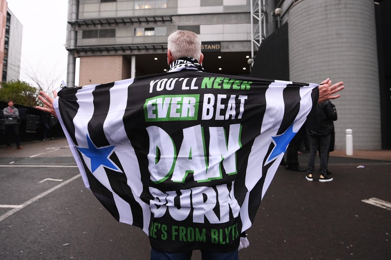A Newcastle United fan is draped in a Dan Burn flag outside the stadium prior to the Premier League match between Newcastle United and Liverpool FC at St. James Park on February 18, 2023