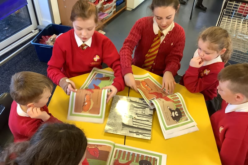 Year 6 and Nursery pupils read books together.