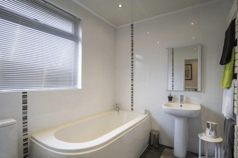 A bathroom featured here, with a generous sized tub and strategically placed taps to avoid any bother