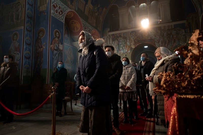 Worshippers queue to receive confession from Serbian Orthodox Christian priest, Father Nenad Popovic during a service of the Nativity of Christ Liturgy in the Serbian Orthodox Church of the Holy Prince Lazar in Bournville, Birmingham, central England on January 7, 2021. The Lazarica church, dedicated to the Holy Prince Lazar, is the first purpose-built Serbian Orthodox church constructed in the UK and is decorated in a 14th Century Byzantine-Morava artistic style. (Photo by OLI SCARFF / AFP) (Photo by OLI SCARFF/AFP via Getty Images)