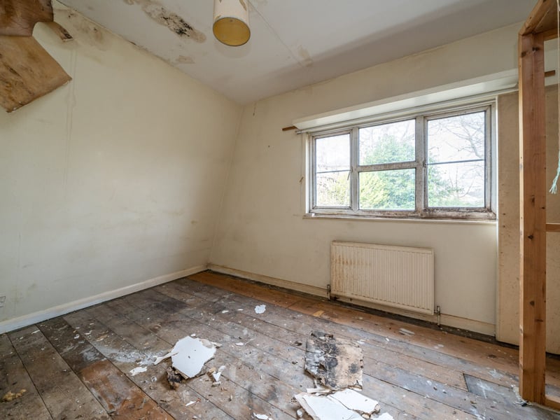 A bedroom with damaged ceiling