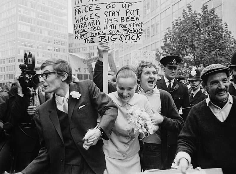 The wedding of Peter Oxley and Alena Czeknovska at Caxton Hall clashes peaceably with a dustmen’s protest during a period of industrial action, October 3, 1969. Dustman Billy MaGinnis waves a placard behind the heads of the happy couple.  (Photo by Norman Potter/Express/Getty Images)