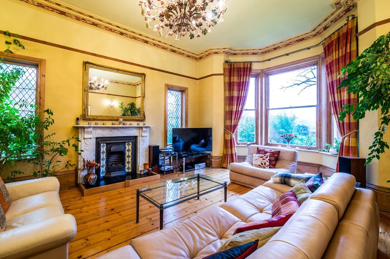 This lounge area features a wide bay window, traditional fireplace and white leather sofas