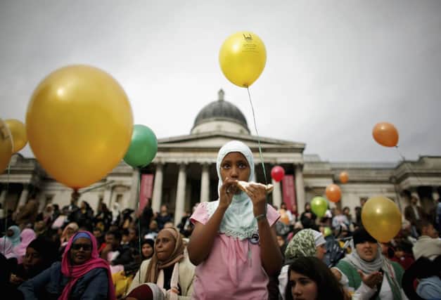 A young Muslim girl eats a sandwich as she looks on during Eid al-Fitr festivities on October 28, 2006 in London, England. (Photo by Daniel Berehulak/Getty Images)