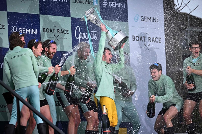 Cambridge President Ollie Boyne is showered with champagne as he lifts the trophy.