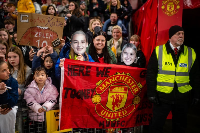 Young fans hold up flags and banners for United favourites Ella Toone, Alessia Russo and Katie Zelem