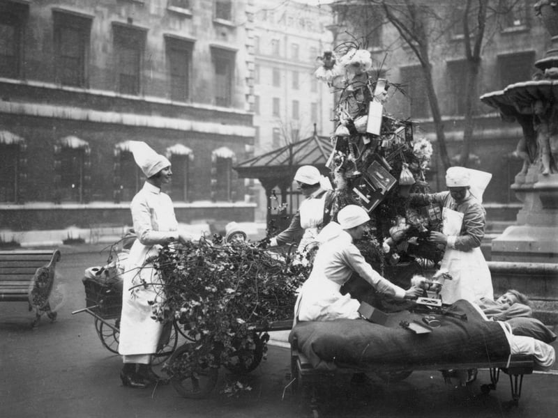 December 23 1929:  Nurses at St Bartholomew’s Hospital in London distributing toys to young patients using a portable Christmas tree which can be wheeled around the hospital grounds.  (Photo by Puttnam /Topical Press Agency/Getty Images)