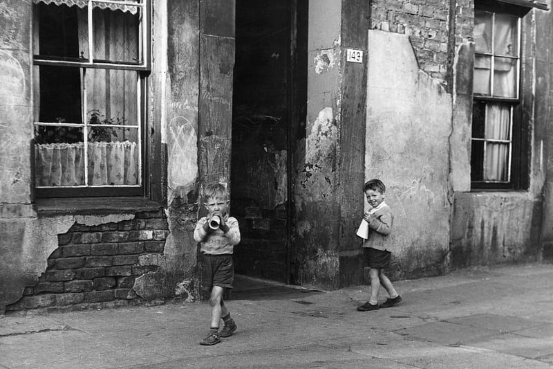 Two young boys playing outside in the Gorbals district of Glasgow, the run-down tenement behind them soon to be demolished (Photo by B Marshall/Getty Images)